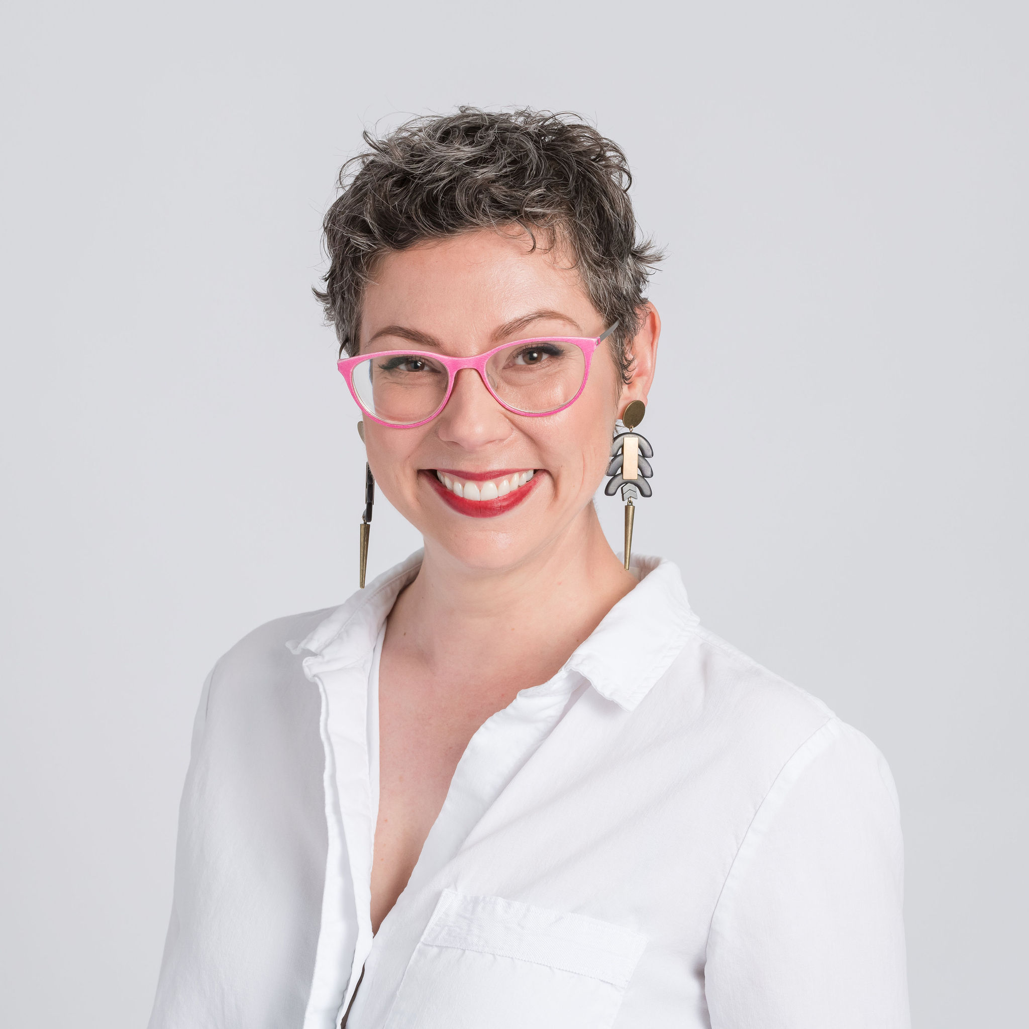 Allison Puryear, LCSW, feminist therapist for women attorneys, smiling in a white blouse and pink glasses