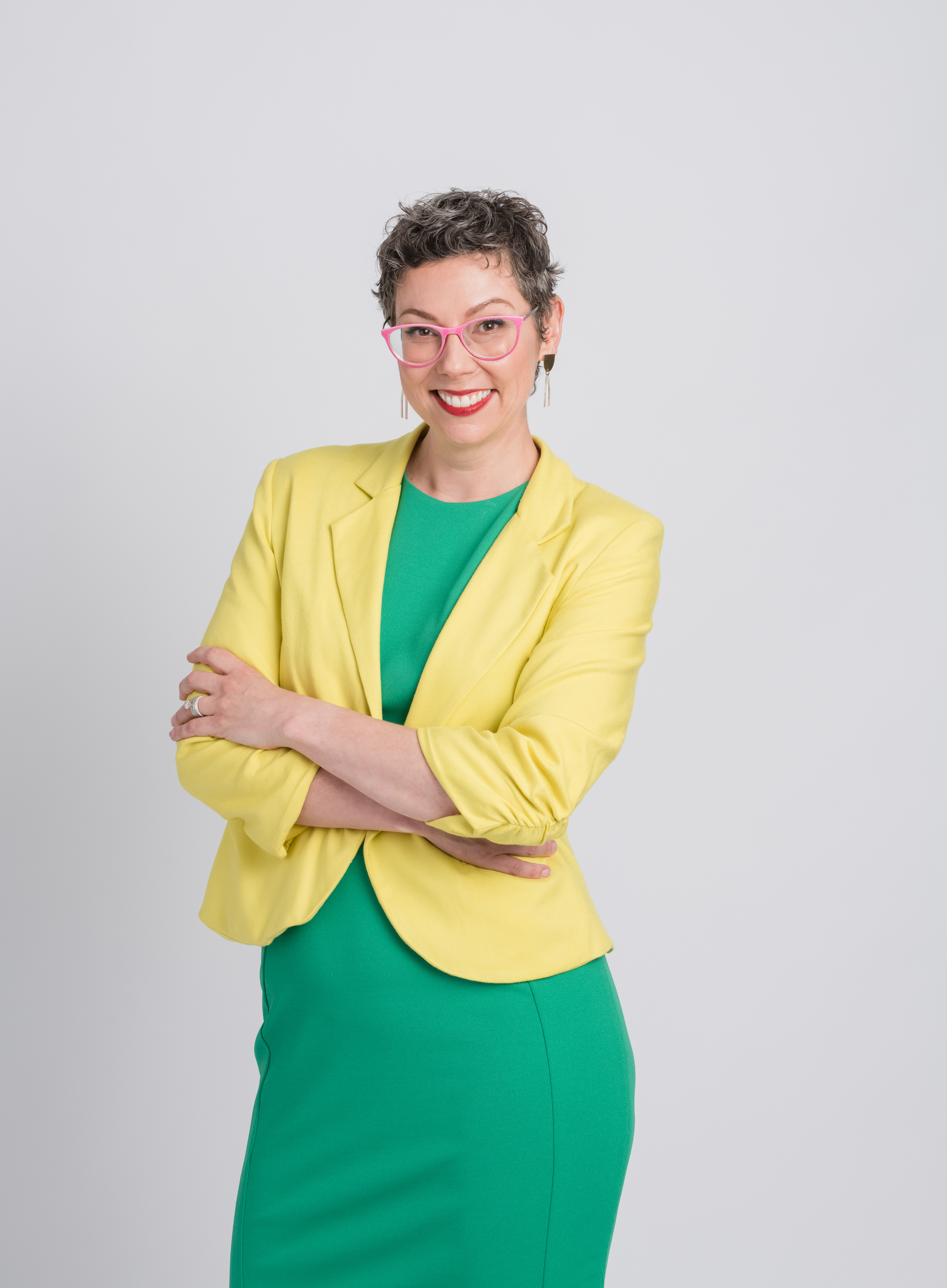 Allison Puryear, LCSW, feminist therapist for women attorneys, wearing a yellow blazer and smiling with arms crossed