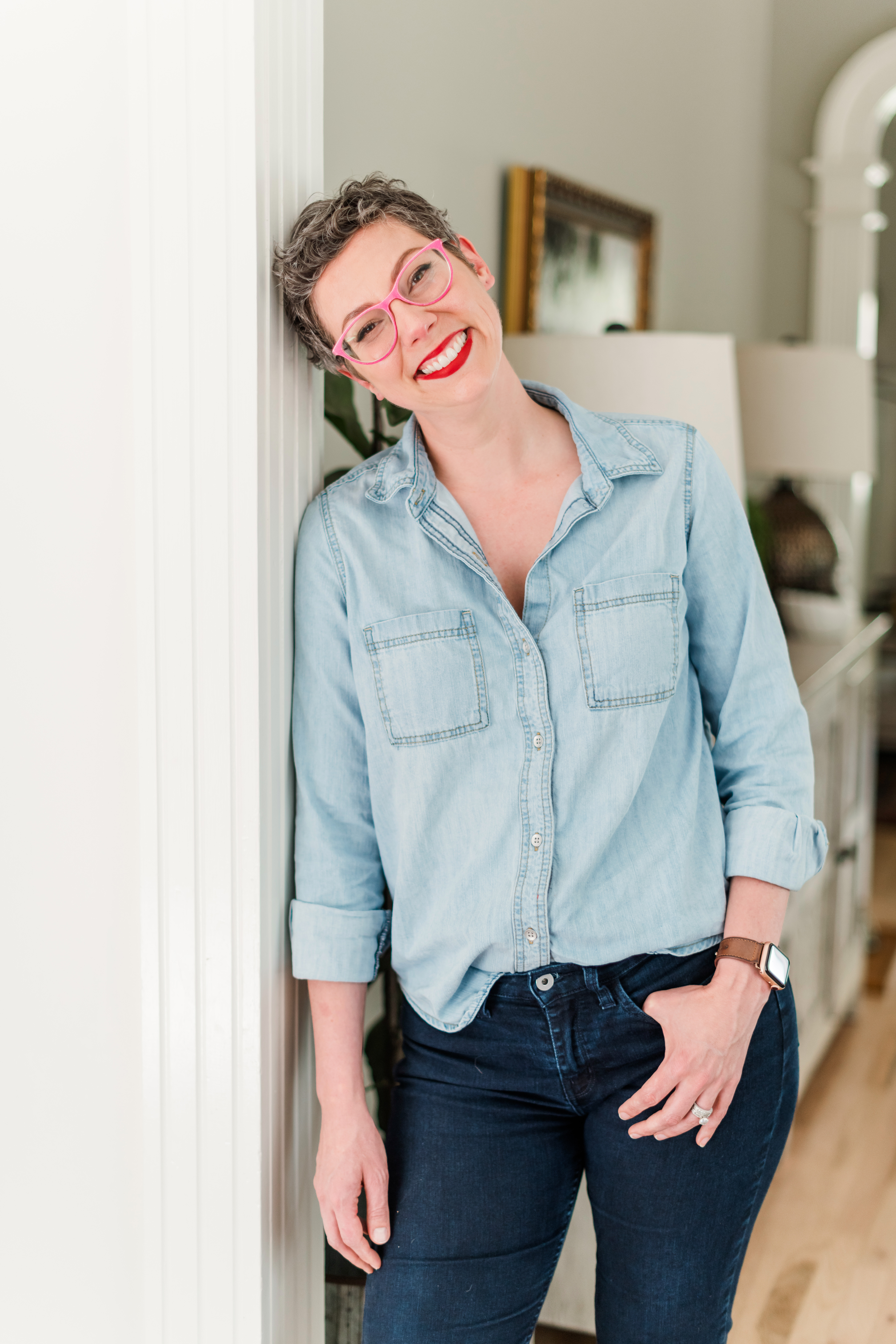 Allison Puryear, LCSW, leaning against a doorframe laughing, wearing a denim shirt